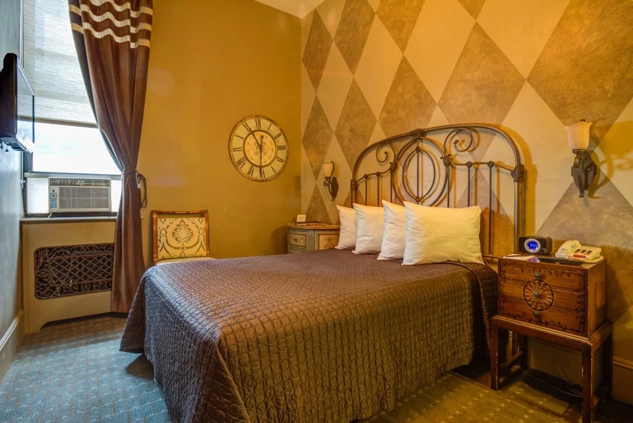 Seton guest room with iron bed and diamond-pattern wall